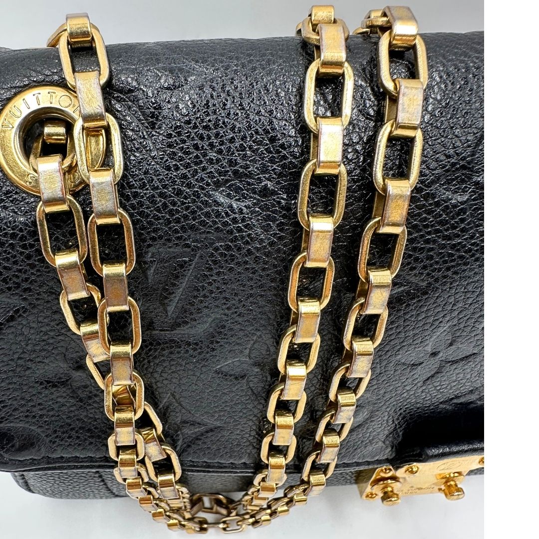 Dettagli catene scolorite di una borsa Louis Vuitton in pelle nera monogram Empreinte con parti metalliche dorate; munita di una tracolla scorrevole in catena. Indossabile a spalla e a tracolla.