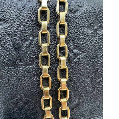 Dettagli catene di una borsa Louis Vuitton in pelle nera monogram Empreinte con parti metalliche dorate; munita di una tracolla scorrevole in catena. Indossabile a spalla e a tracolla.