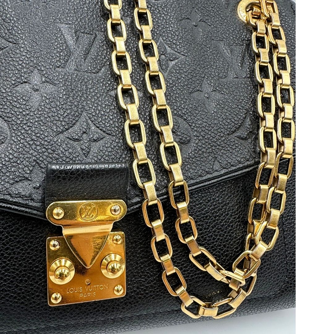 Dettagli catene di una borsa Louis Vuitton in pelle nera monogram Empreinte con parti metalliche dorate; munita di una tracolla scorrevole in catena. Indossabile a spalla e a tracolla.