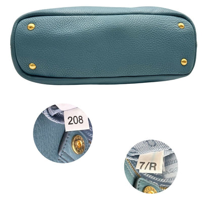 base Borsa Tote Prada in pelle martellata color teal con parti metalliche dorate; munita di doppi manici, indossabile a spalla. Completa di dustbag, di lusso, originale, usata.