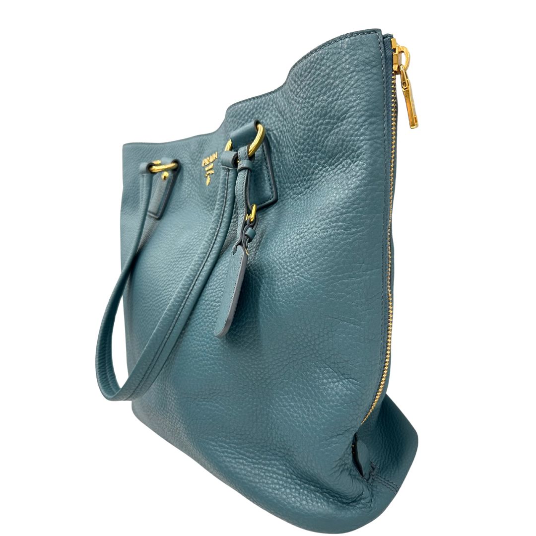 lato Borsa Tote Prada in pelle martellata color teal con parti metalliche dorate; munita di doppi manici, indossabile a spalla. Completa di dustbag, di lusso, originale, usata. 