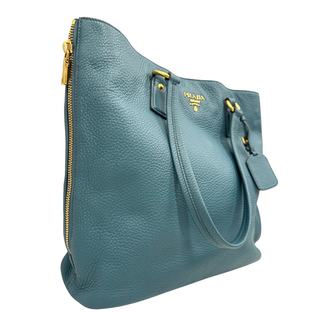 lato Borsa Tote Prada in pelle martellata color teal con parti metalliche dorate; munita di doppi manici, indossabile a spalla. Completa di dustbag, di lusso, originale, usata. 