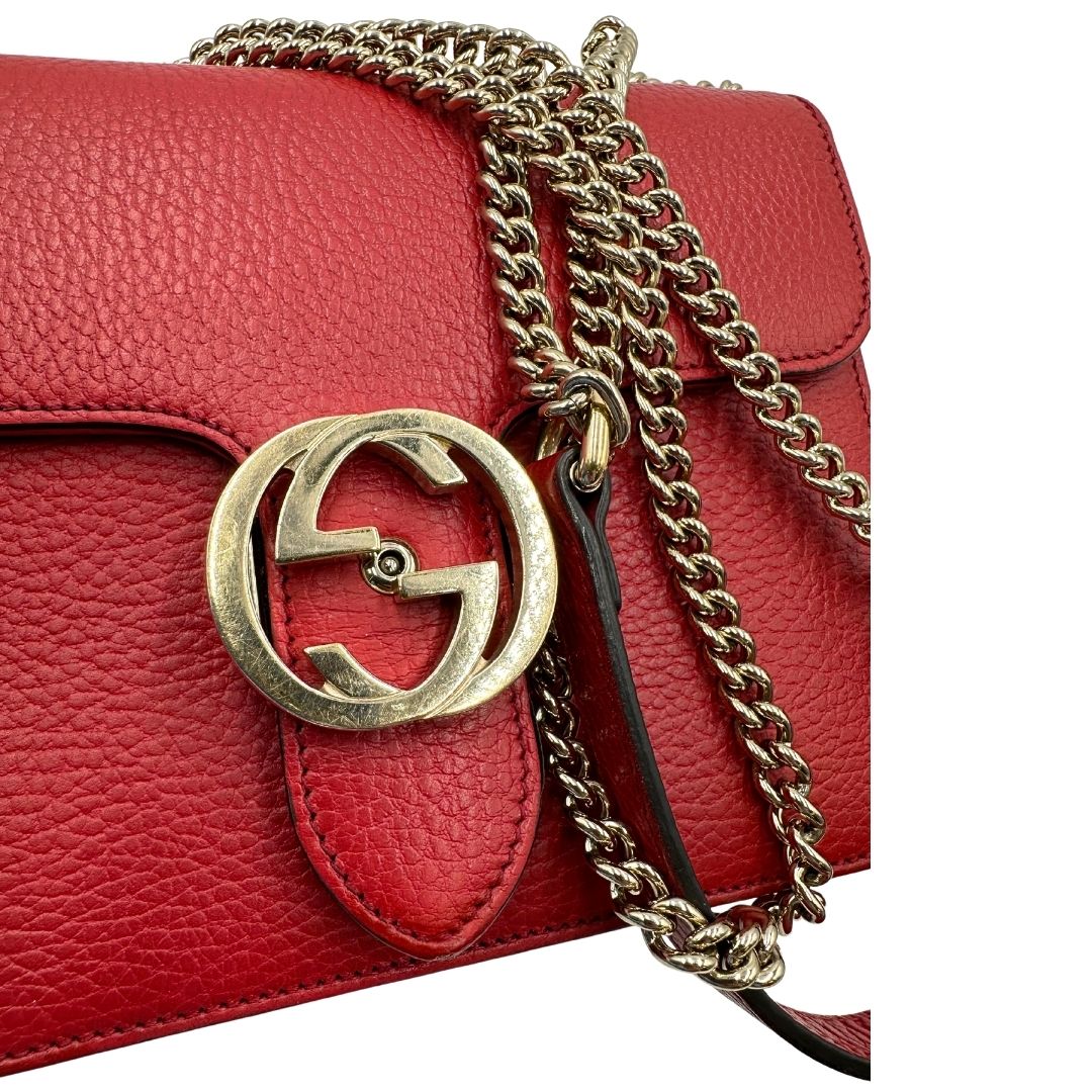 Parti metalliche di una borsa Gucci Interlocking in pelle martellata rossa con parti metalliche dorate. Munita di una tracolla scorrevole in catena non amovibile e spallaccio in pelle. Chiusura con doppie G incrociate. Completa di dustbag. Indossabile a spalla o a tracolla.