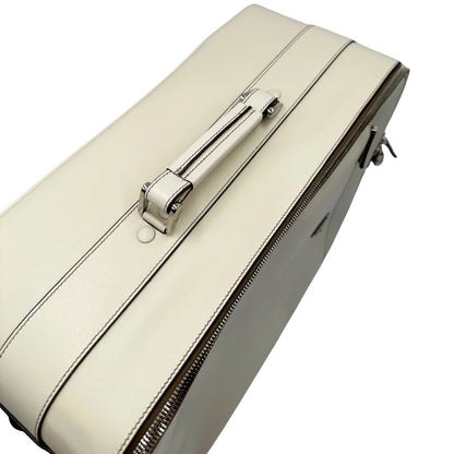 Vista superiore di una valigia Prada in pelle saffiano bianco latte e finiture nere, con dettagli metallici argentati. L’interno è foderato in tessuto jacquard con motivo logo Prada, dotato di cinghie regolabili per fissare il contenuto e tasca con zip. Dispone di doppia chiusura con cerniera e lucchetto numerico in metallo argentato, manico superiore e laterale in pelle, maniglia estraibile e ruote posteriori per facilitarne il trasporto. Completa di dustbag, clochette porta address e card d'autenticità.