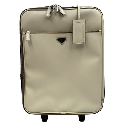 Front di una valigia Prada in pelle saffiano bianco latte e finiture nere, con dettagli metallici argentati. L’interno è foderato in tessuto jacquard con motivo logo Prada, dotato di cinghie regolabili per fissare il contenuto e tasca con zip. Dispone di doppia chiusura con cerniera e lucchetto numerico in metallo argentato, manico superiore e laterale in pelle, maniglia estraibile e ruote posteriori per facilitarne il trasporto. Completa di dustbag, clochette porta address e card d'autenticità.