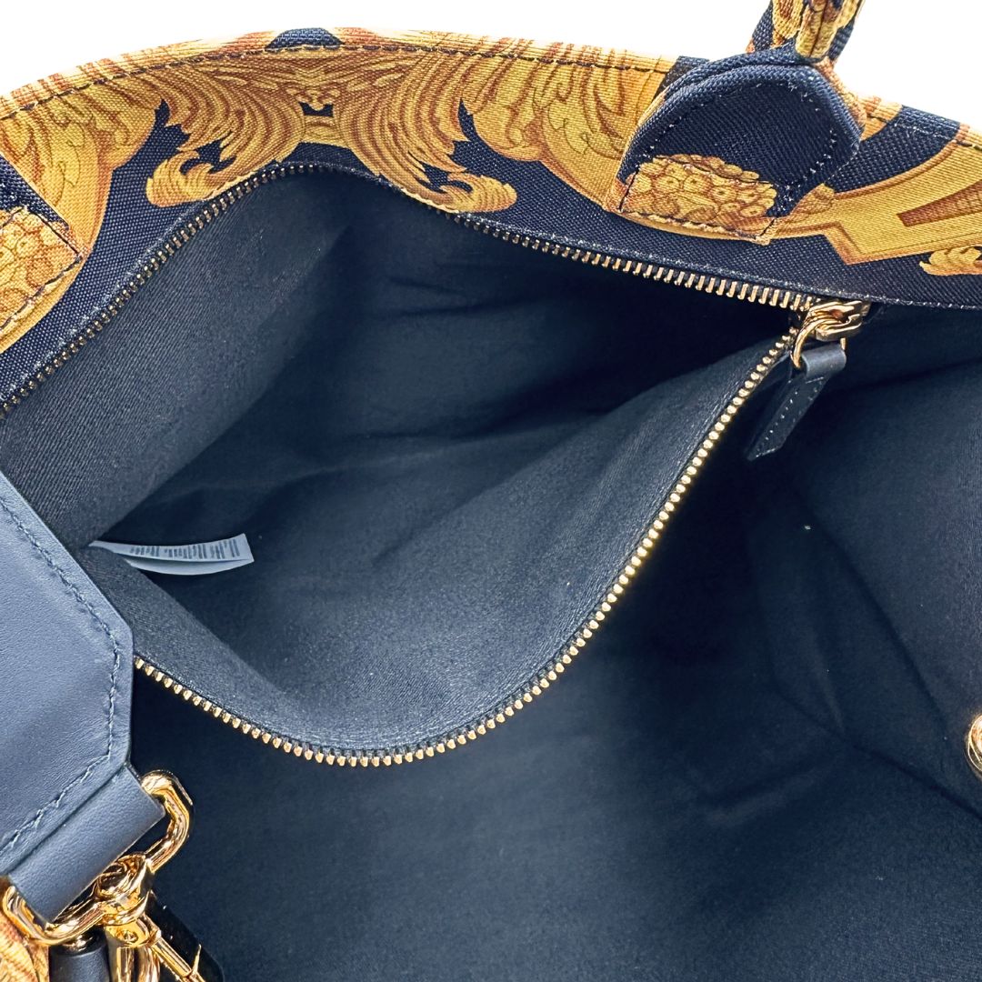 Interno di una borsa Versace in tela com motivo jacquard barocco in nero e giallo tipico della Maison. Presenta doppi manici stondati e una tracolla amovibile in tessuto motivo greca, con dettagli in pelle neri. Completa di dustbag.