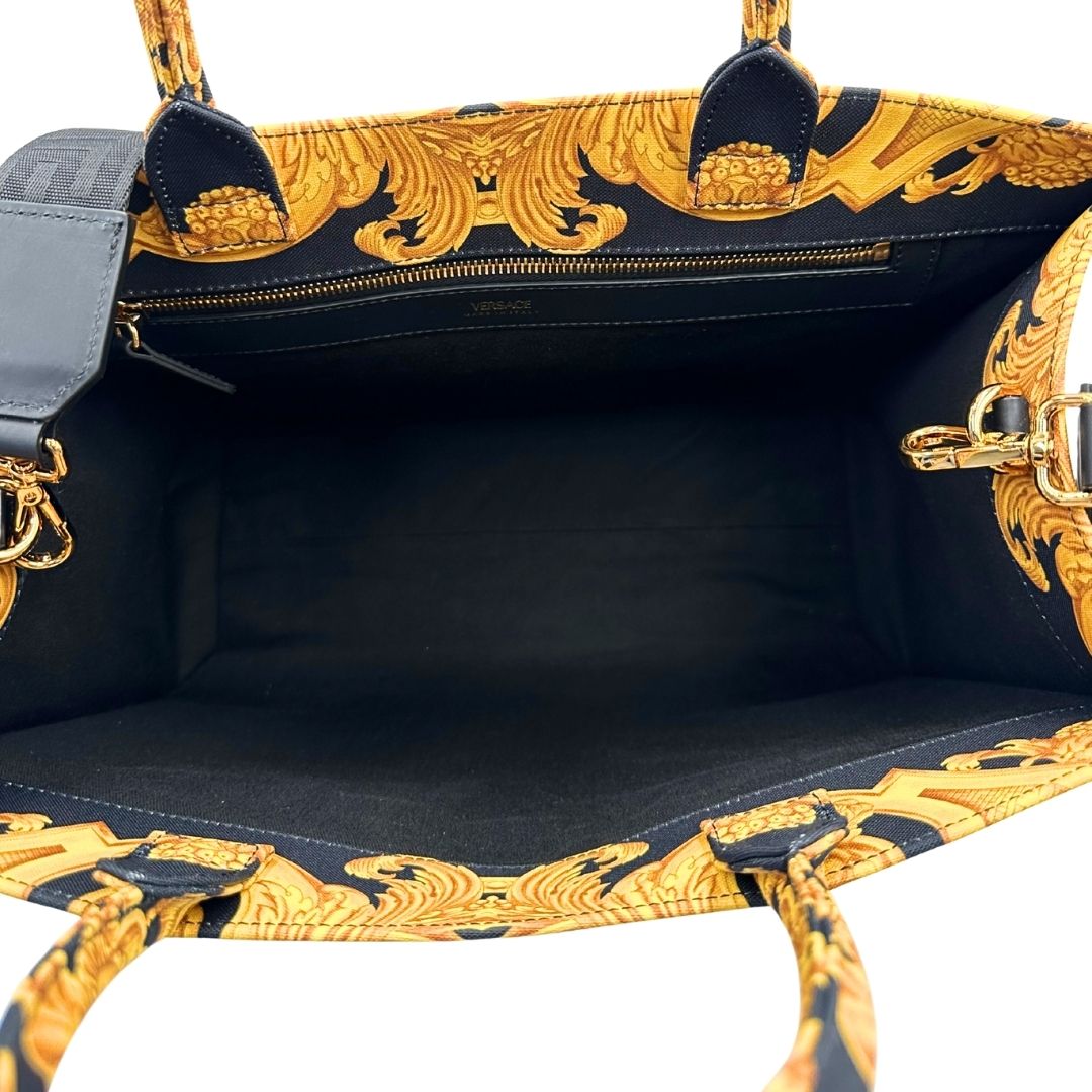 Interno di una borsa Versace in tela com motivo jacquard barocco in nero e giallo tipico della Maison. Presenta doppi manici stondati e una tracolla amovibile in tessuto motivo greca, con dettagli in pelle neri. Completa di dustbag.