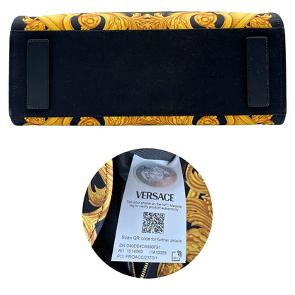 Base e codice di una borsa Versace in tela com motivo jacquard barocco in nero e giallo tipico della Maison. Presenta doppi manici stondati e una tracolla amovibile in tessuto motivo greca, con dettagli in pelle neri. Completa di dustbag.