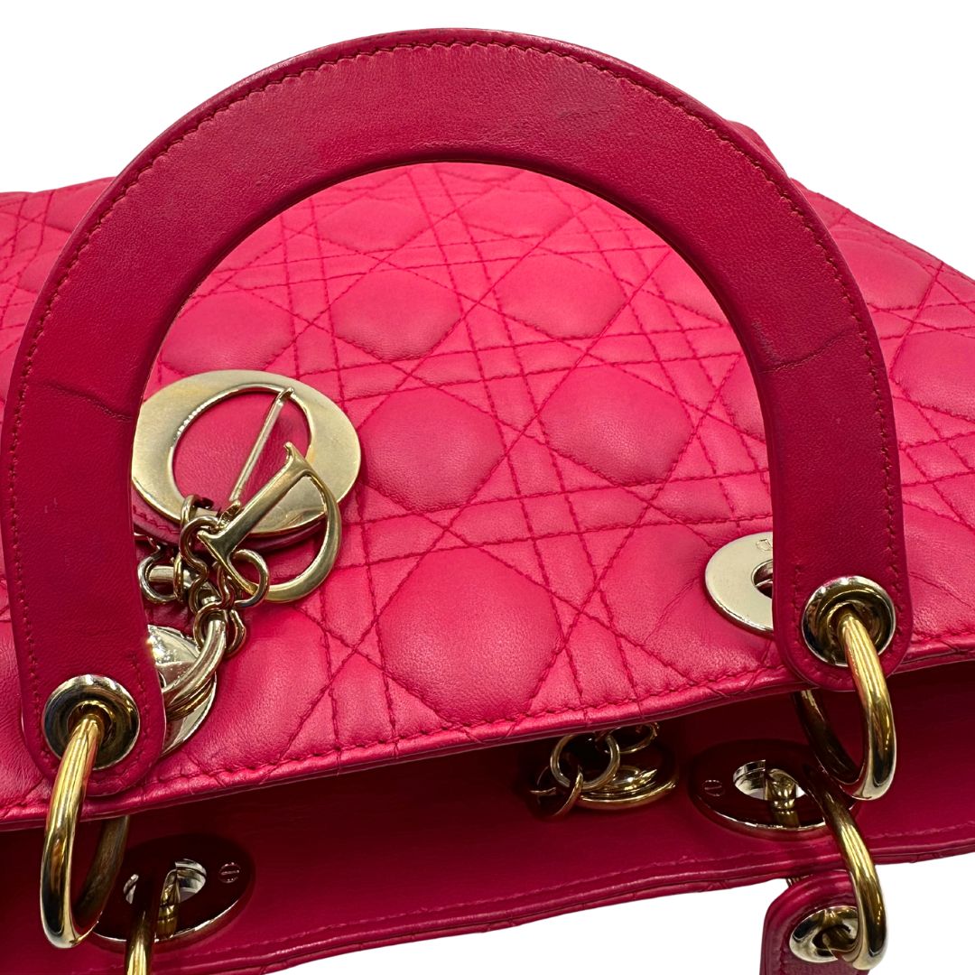 Manici di una borsa Lady Dior Large in pelle fucsia in trama cannage. Doppi manici rigidi, con parti metalliche dorate. Completa di dustbag. Indossabile a mano.