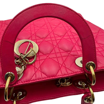 Manici di una borsa Lady Dior Large in pelle fucsia in trama cannage. Doppi manici rigidi, con parti metalliche dorate. Completa di dustbag. Indossabile a mano.