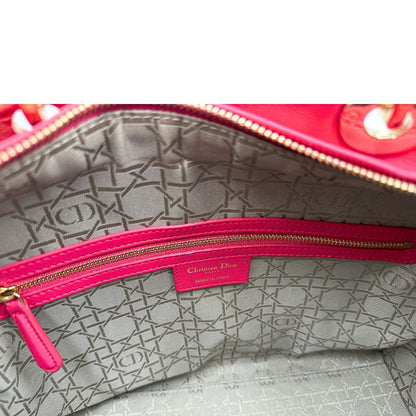 Interno di una borsa Lady Dior Large in pelle fucsia in trama cannage. Doppi manici rigidi, con parti metalliche dorate. Completa di dustbag. Indossabile a mano.