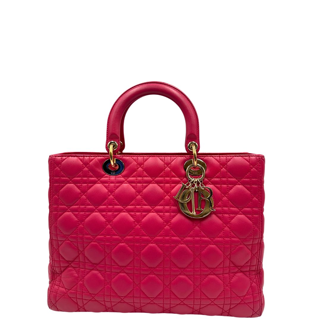 Front di una borsa Lady Dior Large in pelle fucsia in trama cannage. Doppi manici rigidi, con parti metalliche dorate. Completa di dustbag. Indossabile a mano.