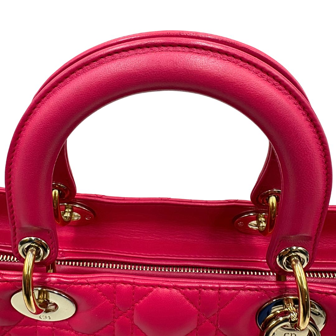 Manici di una borsa Lady Dior Large in pelle fucsia in trama cannage. Doppi manici rigidi, con parti metalliche dorate. Completa di dustbag. Indossabile a mano.