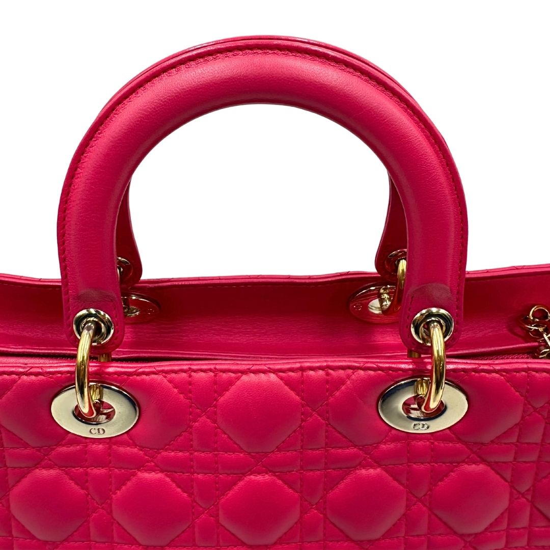 Manici di una borsa Lady Dior Large in pelle fucsia in trama cannage. Doppi manici rigidi, con parti metalliche dorate. Completa di dustbag. Indossabile a mano.