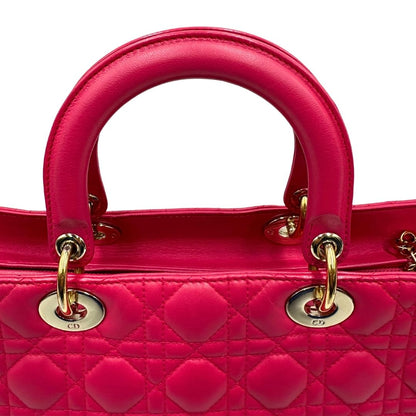 Manici di una borsa Lady Dior Large in pelle fucsia in trama cannage. Doppi manici rigidi, con parti metalliche dorate. Completa di dustbag. Indossabile a mano.