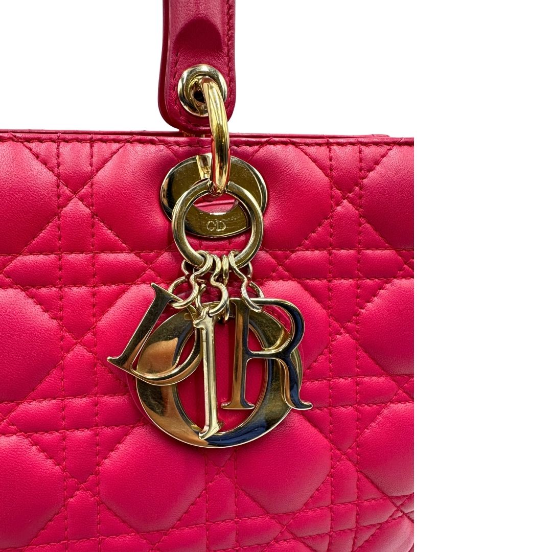 Charm di una borsa Lady Dior Large in pelle fucsia in trama cannage. Doppi manici rigidi, con parti metalliche dorate. Completa di dustbag. Indossabile a mano.