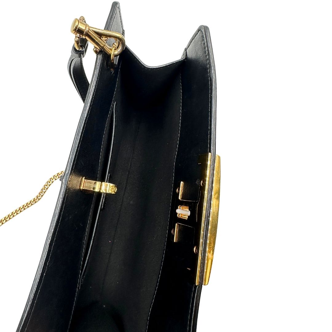 Interno di una borsa Tod's in pelle nera con parti metalliche dorate; munita di una tracolla in catena non amovibile e non regolabile e di un polsino staccabile in pelle. Completa di doppie dustbag.