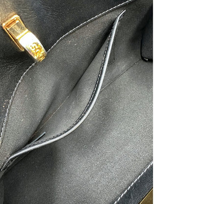 Interno di una borsa Tod's in pelle nera con parti metalliche dorate; munita di una tracolla in catena non amovibile e non regolabile e di un polsino staccabile in pelle. Completa di doppie dustbag.