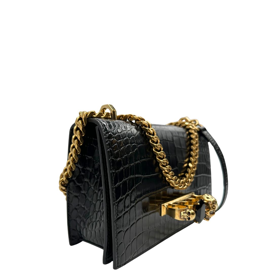 lato Borsa Alexander McQueen in pelle cocco nera con parti metalliche dorate; munita di una tracolla scorrevole in catena con spallaccio in pelle e una knuckle handle impreziosita da teschi e diamanti incastonati. Completa di dustbag, di lusso, originale, eccellenti condizioni 