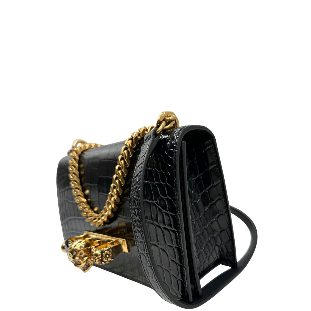 lato Borsa Alexander McQueen in pelle cocco nera con parti metalliche dorate; munita di una tracolla scorrevole in catena con spallaccio in pelle e una knuckle handle impreziosita da teschi e diamanti incastonati. Completa di dustbag, di lusso, originale, eccellenti condizioni 