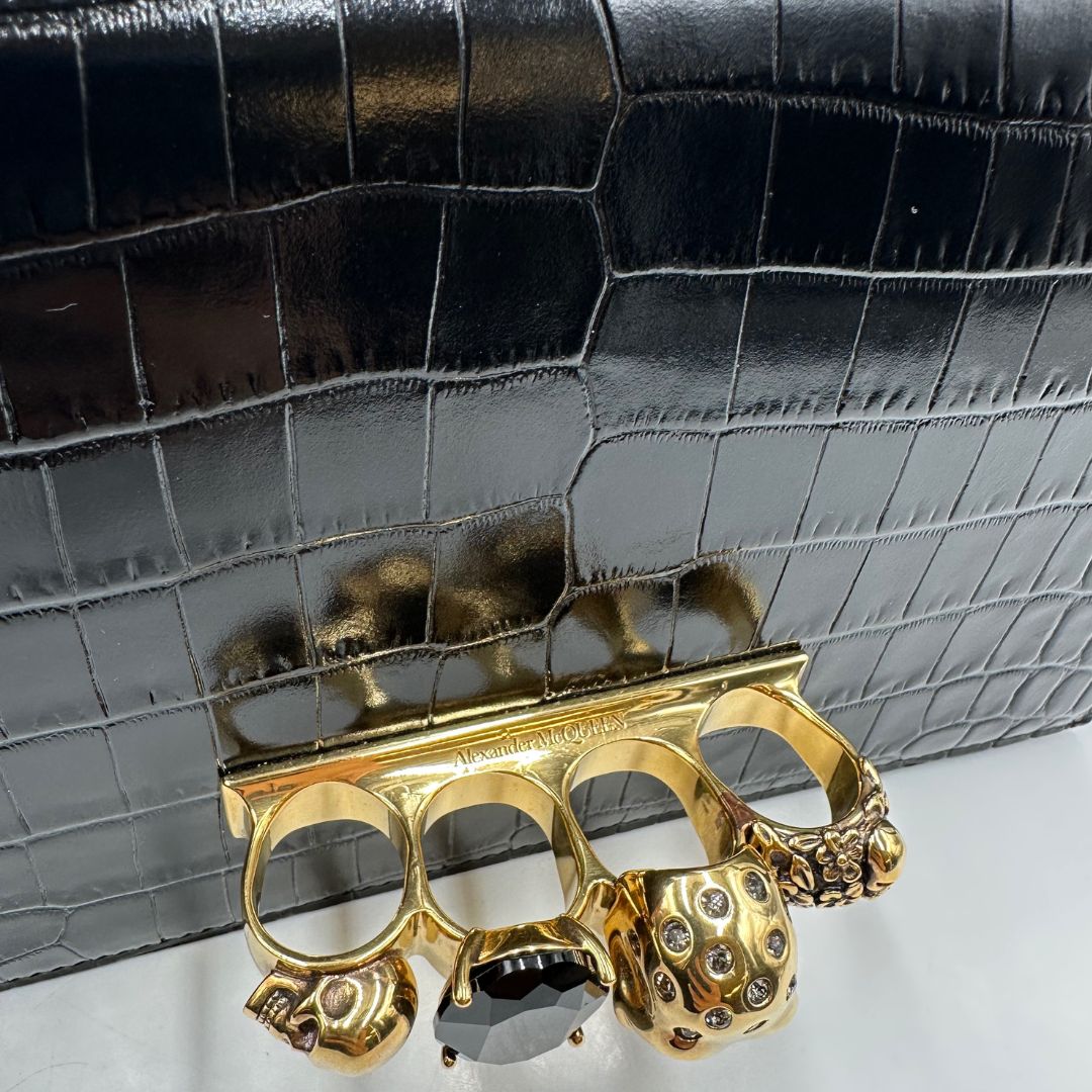 Borsa Alexander McQueen in pelle cocco nera con parti metalliche dorate; munita di una tracolla scorrevole in catena con spallaccio in pelle e una knuckle handle impreziosita da teschi e diamanti incastonati. Completa di dustbag, di lusso, originale, eccellenti condizioni