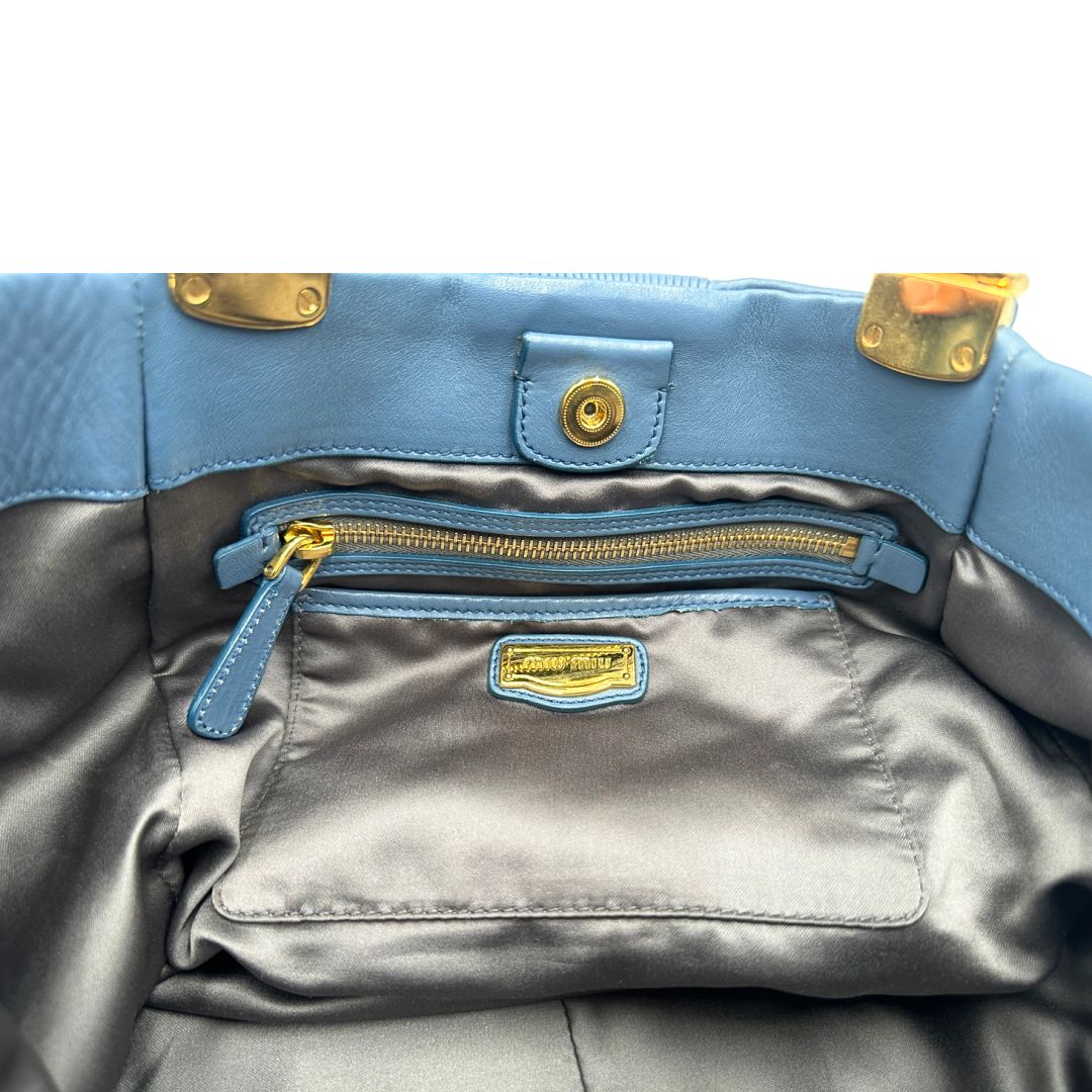 interno Borsa Miu Miu in pelle blu con parti metalliche dorate; munita di doppi manici, indossabile a spalla. Completa di dustbag, di lusso, originale, ottime condizioni. 