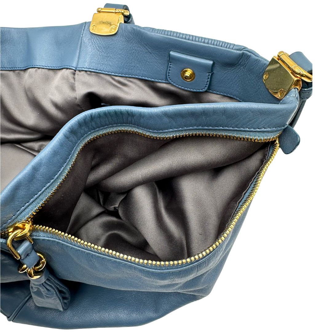 interno Borsa Miu Miu in pelle blu con parti metalliche dorate; munita di doppi manici, indossabile a spalla. Completa di dustbag, di lusso, originale, ottime condizioni. 