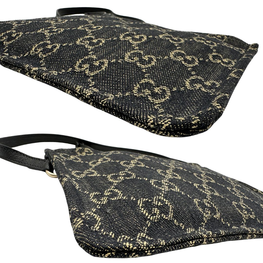 Angoli di un accessorio pochette Gucci in denim nero trama GG con dettagli in pelle neri. Parti metalliche dorate. Completa di dustbag.