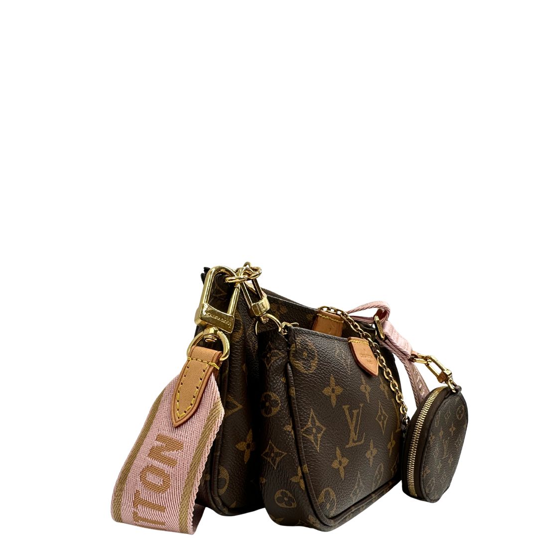 Laterale sinistro di una Multi Pochette Accessoires Louis Vuitton in canvas marrone monogram con dettagli in vacchetta naturale, manico in catena dorata e tracolla in tessuto Jacquard rosa. Dotata del classico mini portamonete rotondo, rimovibile. Munita di scatola.