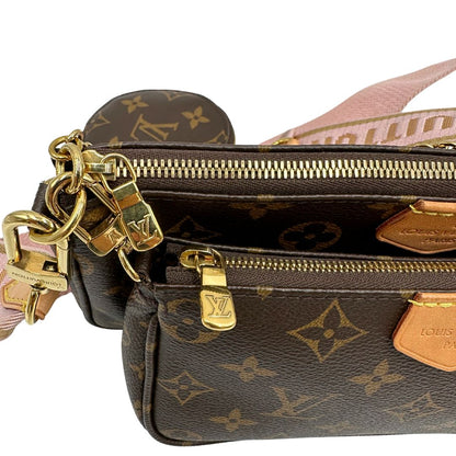 Dettagli metallici di una Multi Pochette Accessoires Louis Vuitton in canvas marrone monogram con dettagli in vacchetta naturale, manico in catena dorata e tracolla in tessuto Jacquard rosa. Dotata del classico mini portamonete rotondo, rimovibile. Munita di scatola.