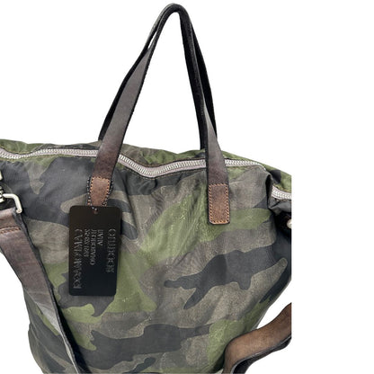 Vista manici di una tote Campomaggi in nylon trama camouflage, con finiture in pelle testa di moro e parti metalliche argentate. Munita di tracolla amovibile e regolabile. Completa di dustbag.