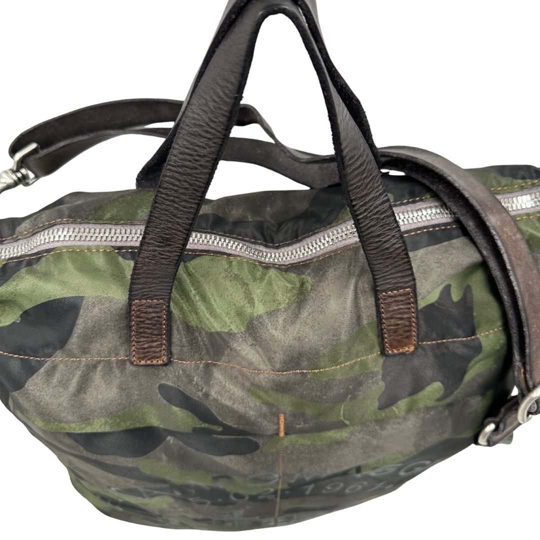 Vista superiore di una tote Campomaggi in nylon trama camouflage, con finiture in pelle testa di moro e parti metalliche argentate. Munita di tracolla amovibile e regolabile. Completa di dustbag.