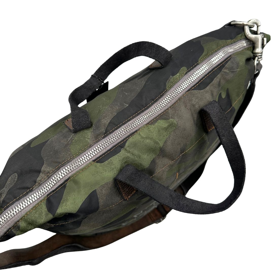 Vista superiore di una tote Campomaggi in nylon trama camouflage, con finiture in pelle testa di moro e parti metalliche argentate. Munita di tracolla amovibile e regolabile. Completa di dustbag.