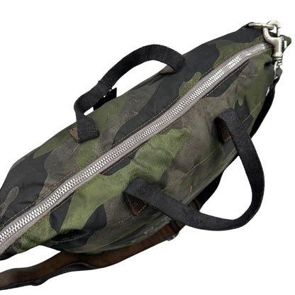 Vista superiore di una tote Campomaggi in nylon trama camouflage, con finiture in pelle testa di moro e parti metalliche argentate. Munita di tracolla amovibile e regolabile. Completa di dustbag.