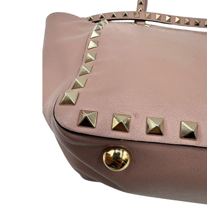 angolo Borsa Valentino Garavani in pelle rosa con parti metalliche dorate; impreziosita da borchie piramidali e munita di doppi manici e una tracolla amovibile. Completa di dustbag, di lusso, originale, usata. 
