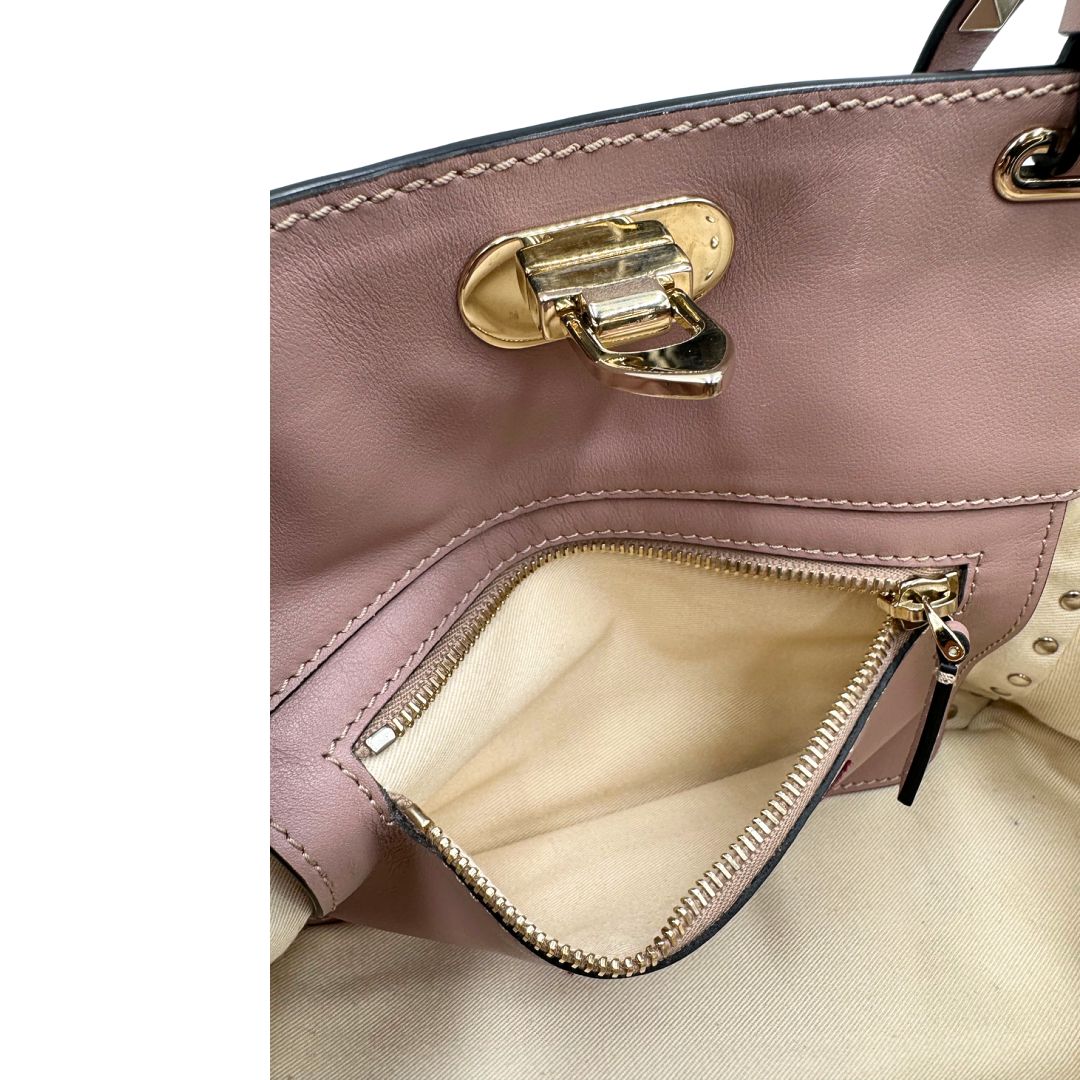 interno Borsa Valentino Garavani in pelle rosa con parti metalliche dorate; impreziosita da borchie piramidali e munita di doppi manici e una tracolla amovibile. Completa di dustbag, di lusso, originale, usata. 