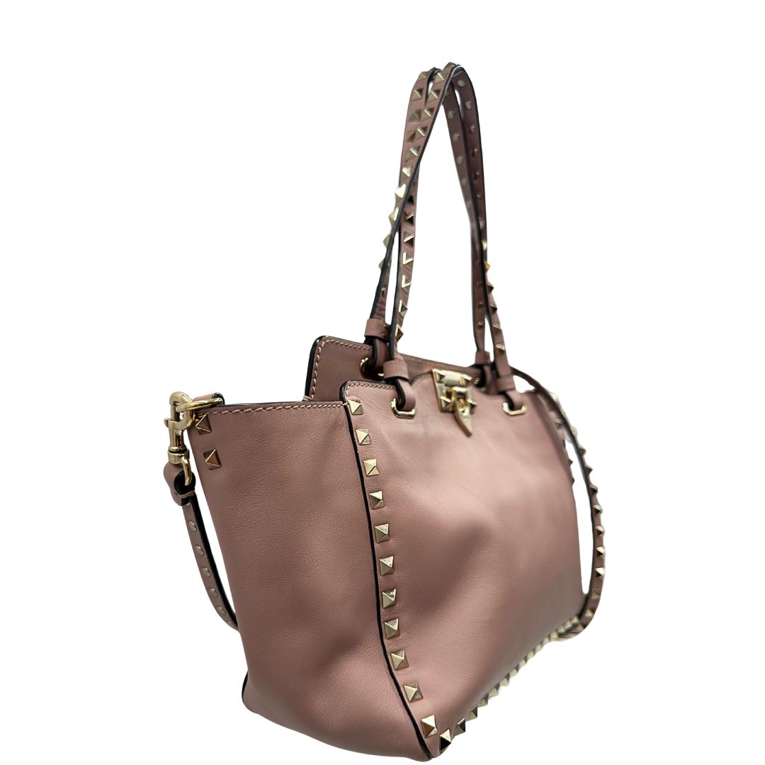 lato Borsa Valentino Garavani in pelle rosa con parti metalliche dorate; impreziosita da borchie piramidali e munita di doppi manici e una tracolla amovibile. Completa di dustbag, di lusso, originale, usata. 