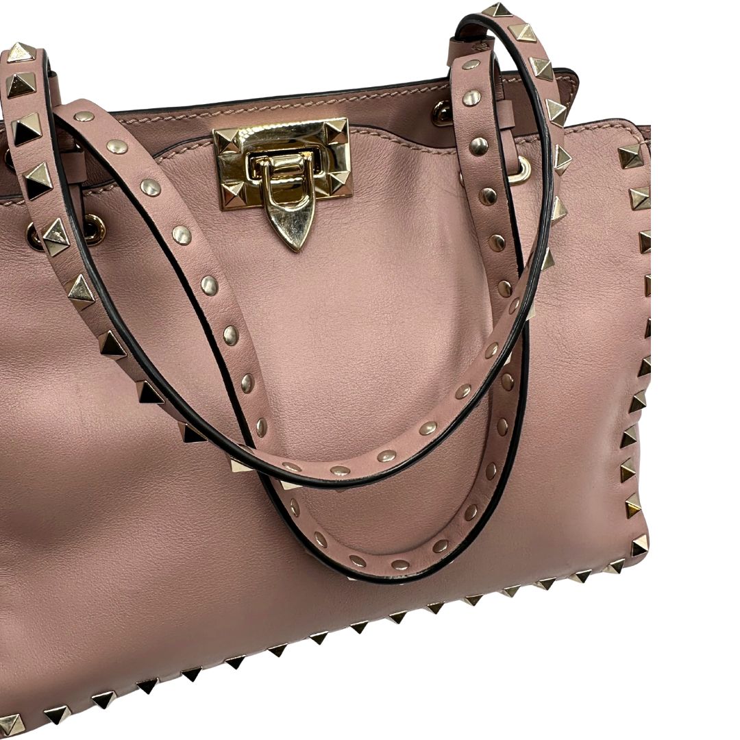 manici Borsa Valentino Garavani in pelle rosa con parti metalliche dorate; impreziosita da borchie piramidali e munita di doppi manici e una tracolla amovibile. Completa di dustbag, di lusso, originale, usata. 