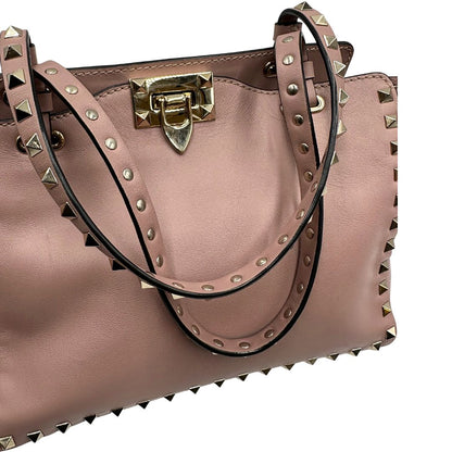 manici Borsa Valentino Garavani in pelle rosa con parti metalliche dorate; impreziosita da borchie piramidali e munita di doppi manici e una tracolla amovibile. Completa di dustbag, di lusso, originale, usata. 