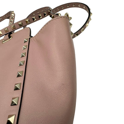 Borsa Valentino Garavani in pelle rosa con parti metalliche dorate; impreziosita da borchie piramidali e munita di doppi manici e una tracolla amovibile. Completa di dustbag, di lusso, originale, usata. 