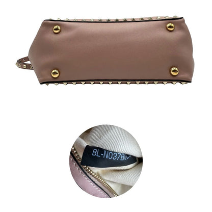 base Borsa Valentino Garavani in pelle rosa con parti metalliche dorate; impreziosita da borchie piramidali e munita di doppi manici e una tracolla amovibile. Completa di dustbag, di lusso, originale, usata.  