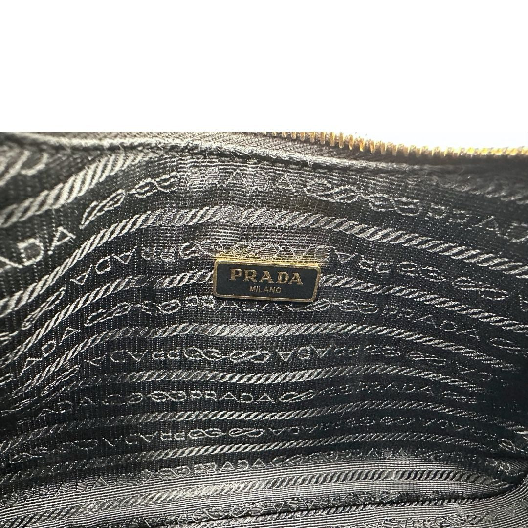 Interno di una borsa Prada in pelle saffiano nera, con parti metalliche dorate. Dotata di una tracolla in tessuto regolabile ed amovibile, con pouch porta monete removibile e di una tracollina in catena. Munita di clochette porta chiavi. Indossabile a spalla o a tracolla. Full set.