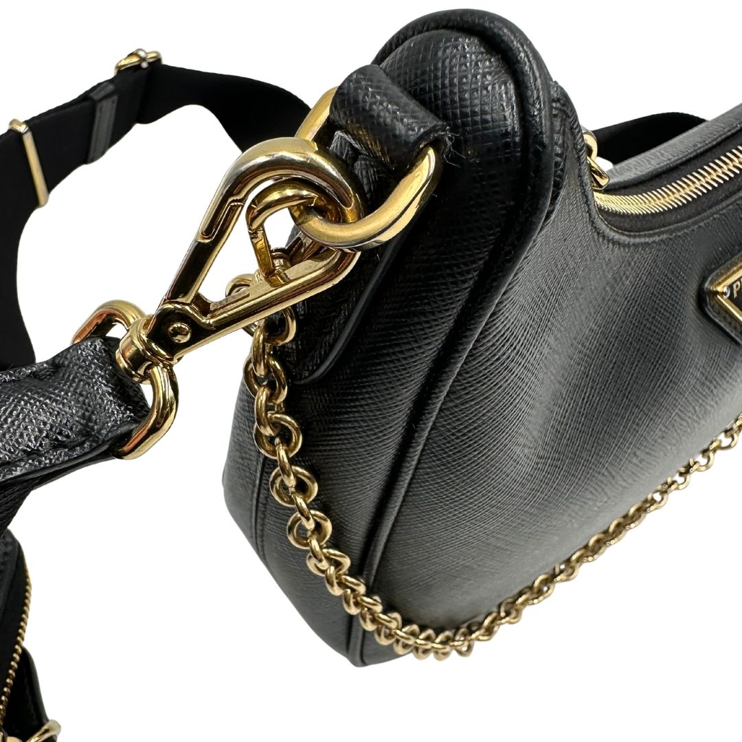 Difetti metalleria di una borsa Prada in pelle saffiano nera, con parti metalliche dorate. Dotata di una tracolla in tessuto regolabile ed amovibile, con pouch porta monete removibile e di una tracollina in catena. Munita di clochette porta chiavi. Indossabile a spalla o a tracolla. Full set.