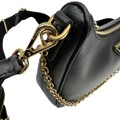 Difetti metalleria di una borsa Prada in pelle saffiano nera, con parti metalliche dorate. Dotata di una tracolla in tessuto regolabile ed amovibile, con pouch porta monete removibile e di una tracollina in catena. Munita di clochette porta chiavi. Indossabile a spalla o a tracolla. Full set.