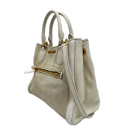 Laterale destro di una borsa Miu Miu in misto lino avorio con finiture in pelle color bianco latte e parti metalliche dorate; munita di doppi manici stondati ed una tracolla amovibile e regolabile. Completa di card d'autenticità. Indossabile a mano e a tracolla.