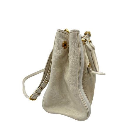 Vista laterale di una borsa Miu Miu in misto lino avorio con finiture in pelle color bianco latte e parti metalliche dorate; munita di doppi manici stondati ed una tracolla amovibile e regolabile. Completa di card d'autenticità. Indossabile a mano e a tracolla.