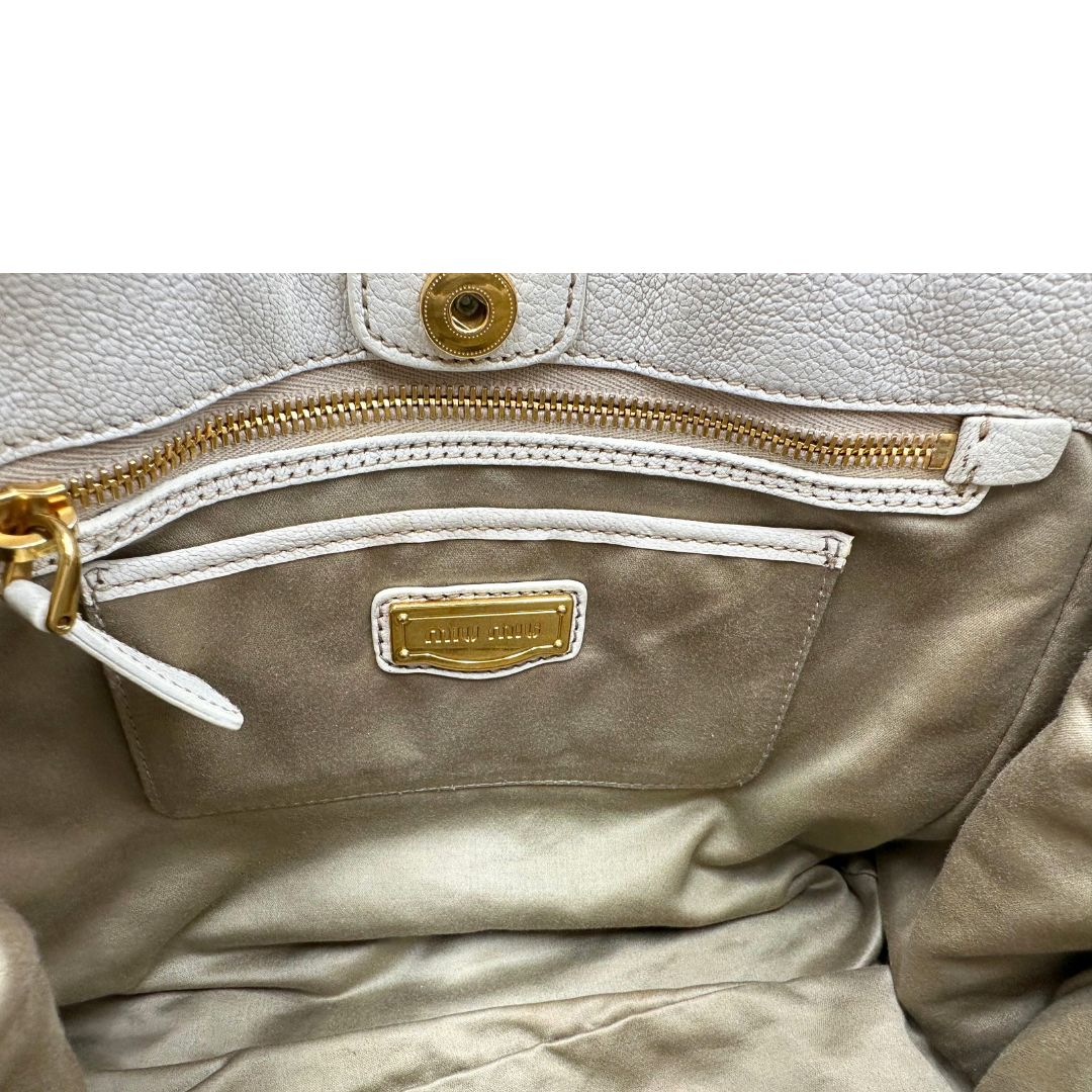Interno di una borsa Miu Miu in misto lino avorio con finiture in pelle color bianco latte e parti metalliche dorate; munita di doppi manici stondati ed una tracolla amovibile e regolabile. Completa di card d'autenticità. Indossabile a mano e a tracolla.