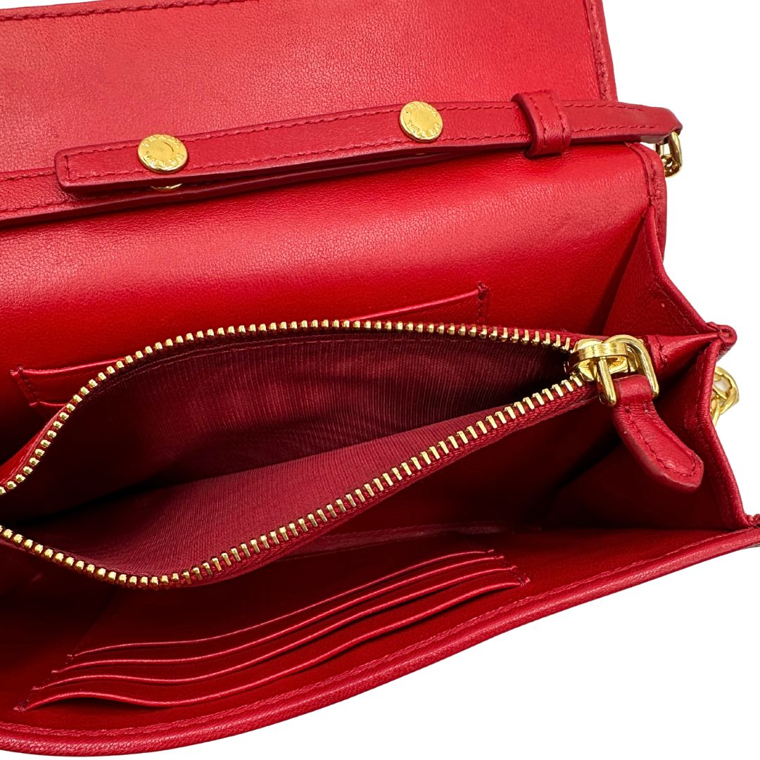 Interno di un wallet Prada in pelle goffrata rossa, impreziosito da logo lettering sul front e specchietto interno; munito di una tracolla in catena amovibile e non regolabile. Completo di scatola.