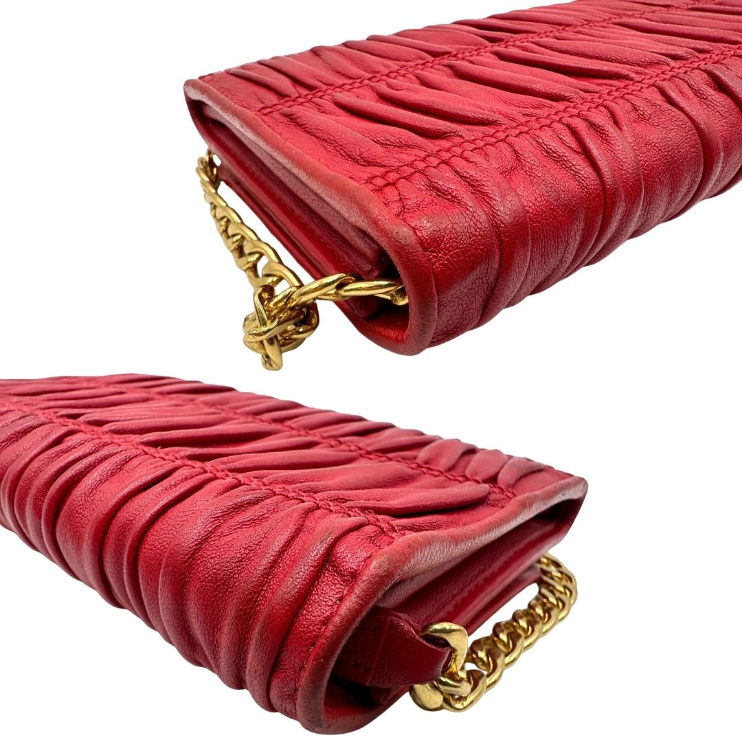 Angoli di un wallet Prada in pelle goffrata rossa, impreziosito da logo lettering sul front e specchietto interno; munito di una tracolla in catena amovibile e non regolabile. Completo di scatola.