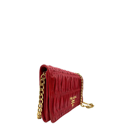 Laterale sinistro di un wallet Prada in pelle goffrata rossa, impreziosito da logo lettering sul front e specchietto interno; munito di una tracolla in catena amovibile e non regolabile. Completo di scatola.
